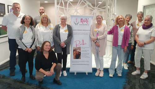 A number of volunteers beside a Reiki Association sign when attending an MNDWA Pamper day giving Reiki to MND clients